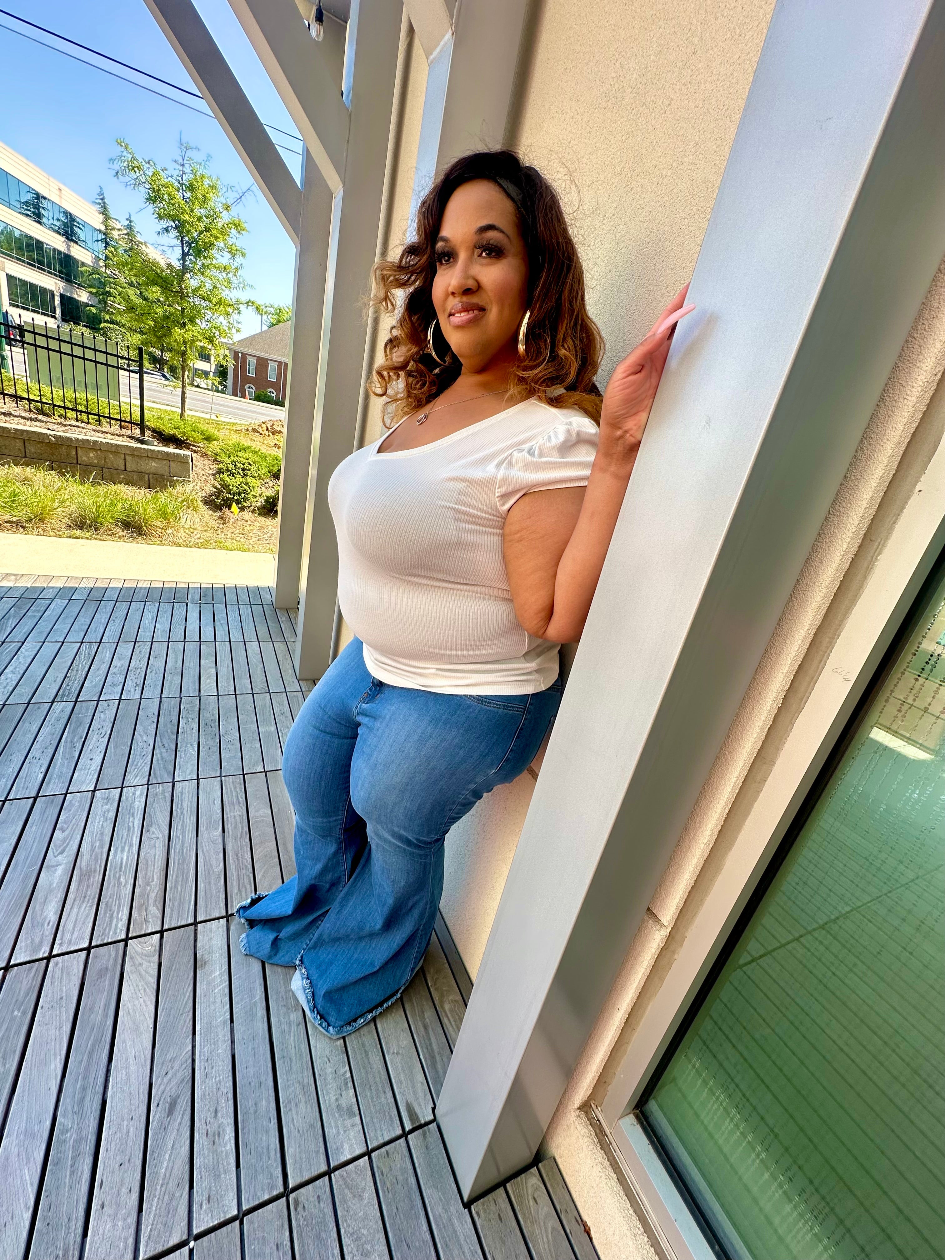 Plus-size tall woman wearing best-fitting bell bottom flare jeans in medium-blue denim, styled for curves and height. Side