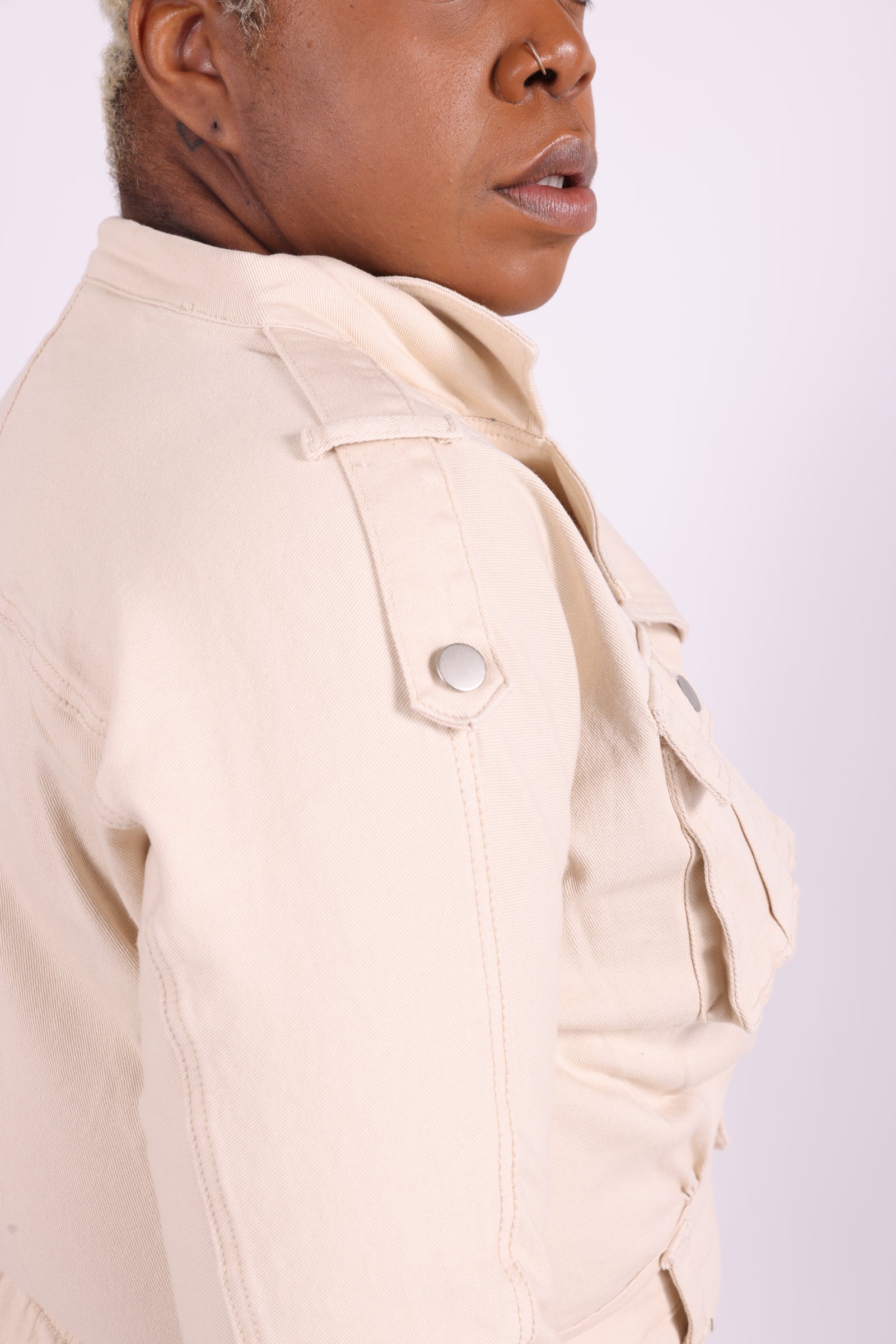 “Plus-size denim romper in ivory with front chest pockets and side leg pockets, short-sleeve, curve-friendly fit with stretch.”
