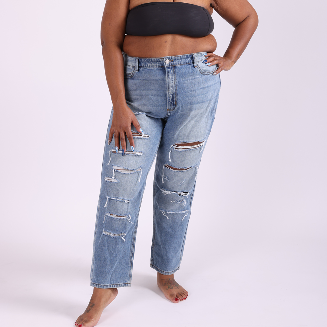 Plus-size woman in Raquel mid-rise rigid boyfriend jeans with front-leg distressed details, styled for a relaxed and structured fit. Full length