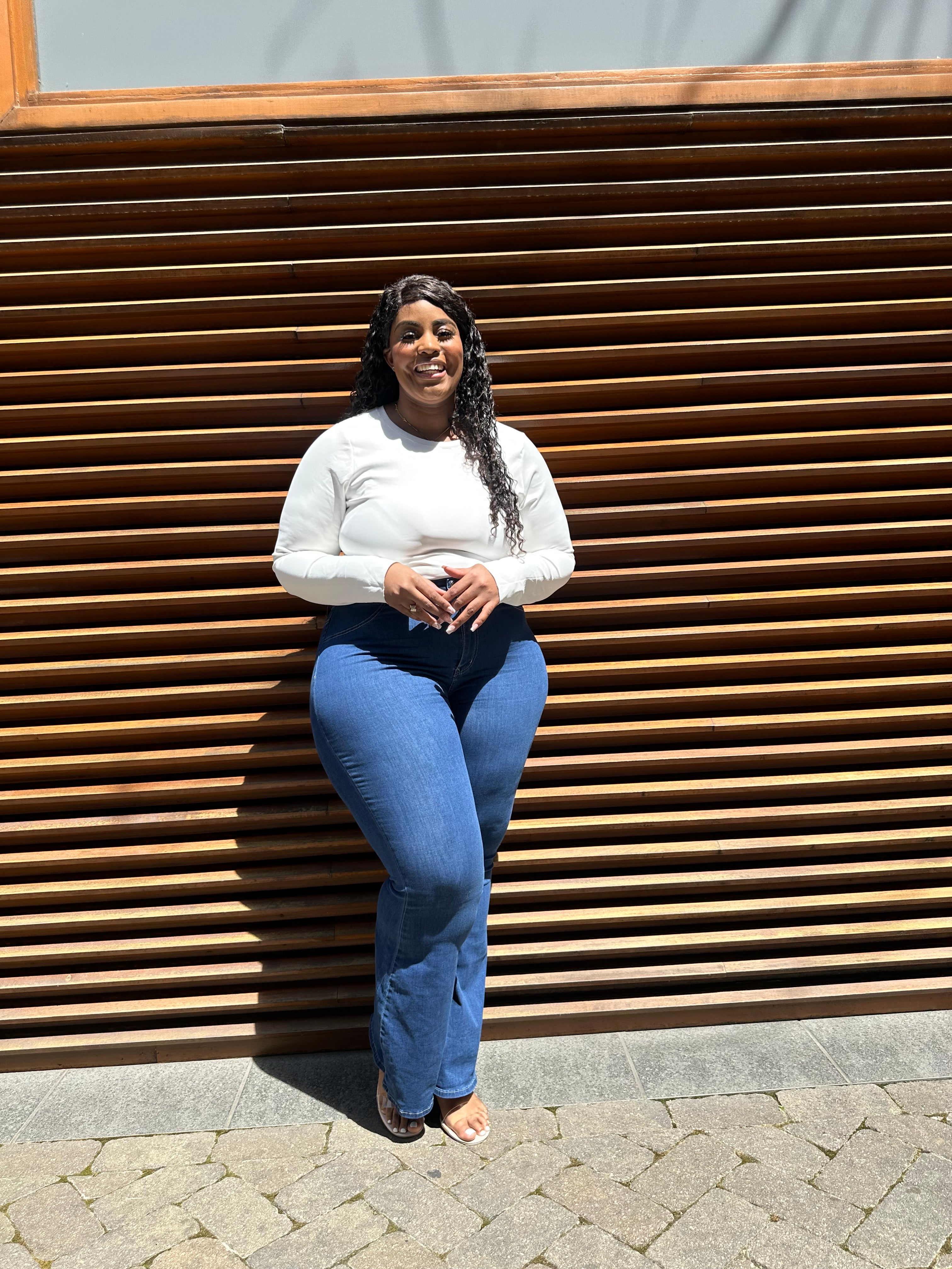 Plus-size tall woman wearing best-fitting bell bottom flare jeans in medium blue denim, styled for curves and height, crossed.