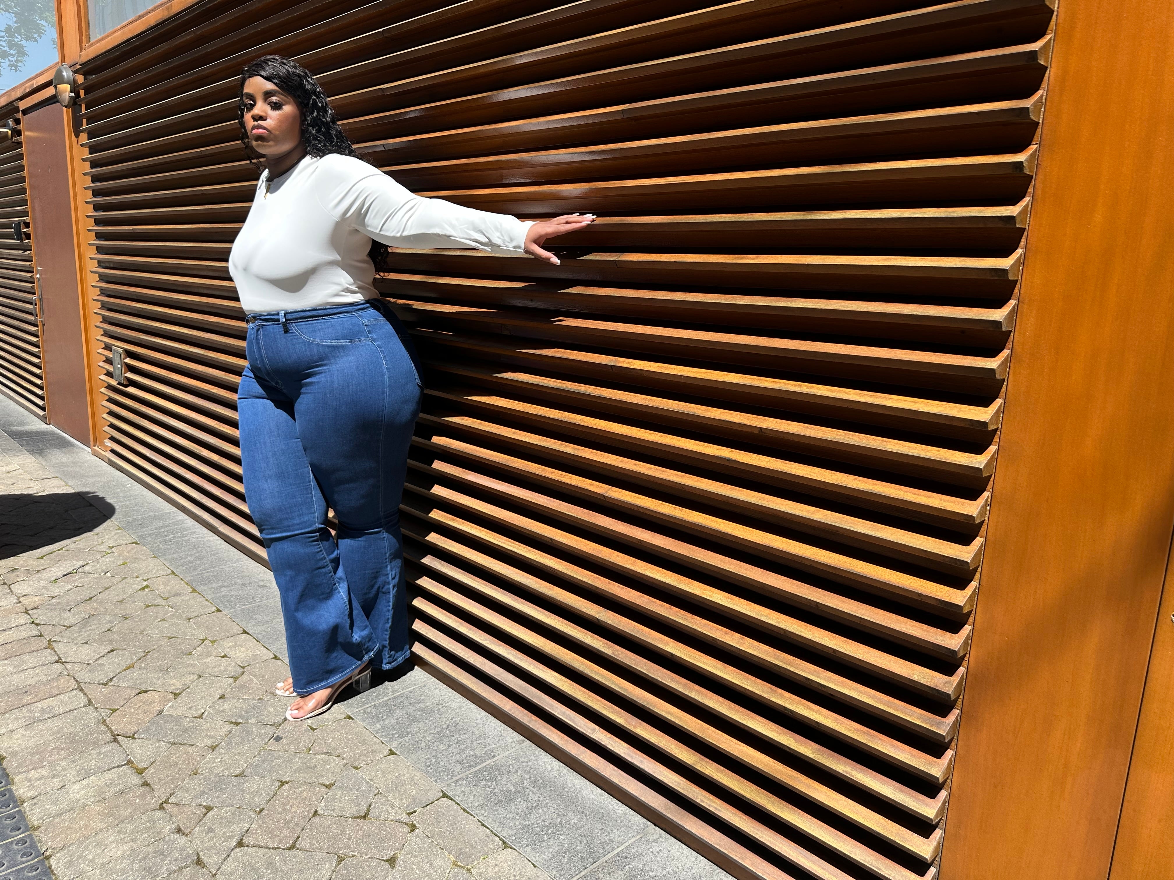 Plus-size tall woman wearing best-fitting bell bottom flare jeans in medium blue denim, styled for curves and height, open-wide.