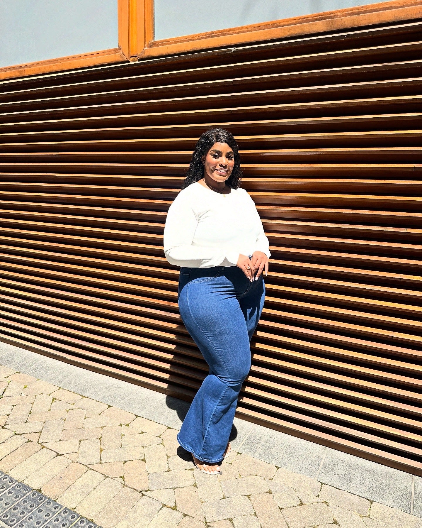 Plus-size tall woman wearing best-fitting bell bottom flare jeans in medium blue denim, styled for curves and height, side flare.